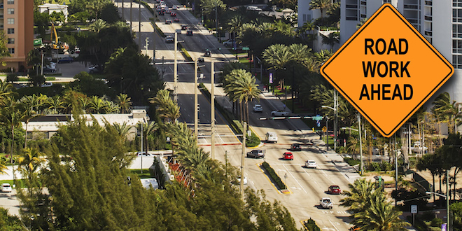 An aerial view of Collins Avenue in Sunny Isles Beach with "Road Work Ahead" Sign superimposed on Top.