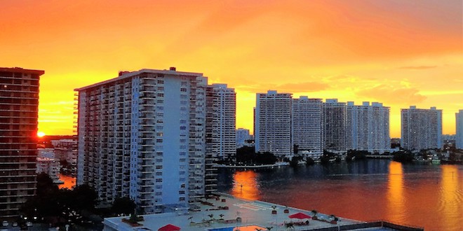 Condominiums on the intracoastal waterway at sunset with orange and yellow skies.