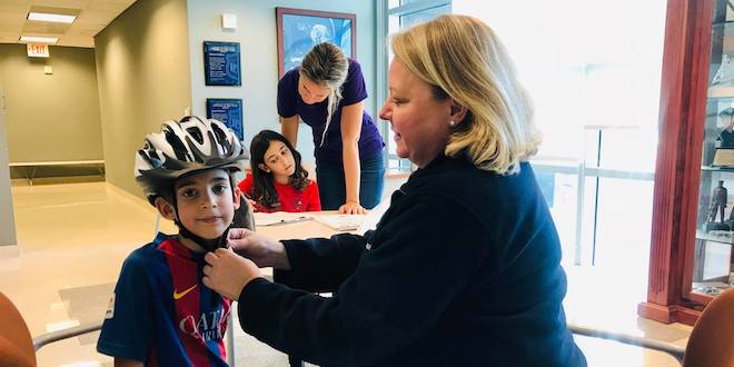 Sandra Block fits a young boy with a free bicycle helmet.