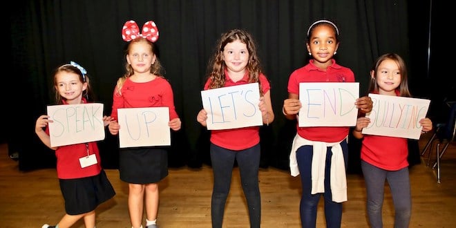 Children holding signs that say "Speak Up Let's End Bullying"