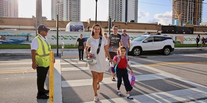 Parents and children using the crosswalk as they walk to school.
