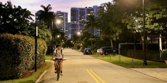 Biker rides down the street in Golden Shores under the light of the new streetlights.
