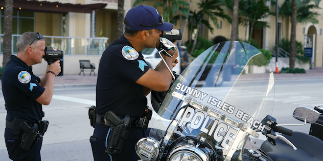 Officers holding radar guns while clocking the speed of passing traffic