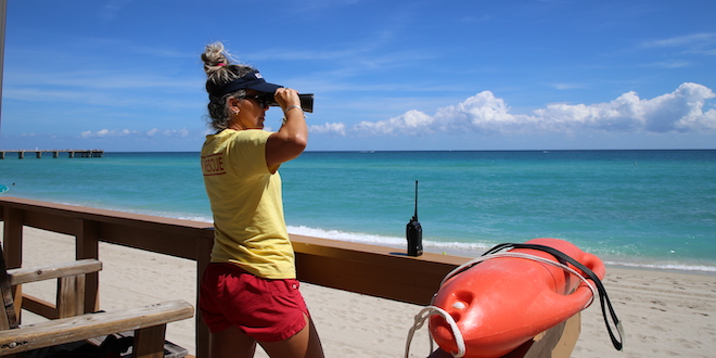 Lifeguard looking through binoculars at ocean