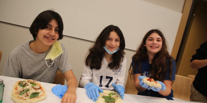 Three teens making pizza at a teens only cooking class