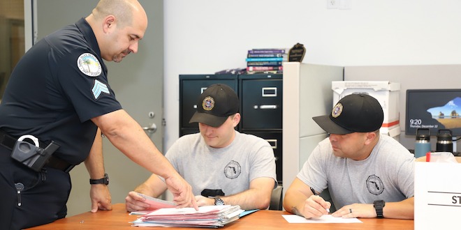 Lt. Zamora pointing to a document on the table in front of two recruits.