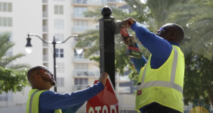 Public Works workers installing lights on a stop sign.