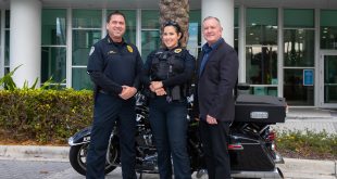 Chief Santiago, Officer Martinez, and City Manager Stan Morris standing in front of motorcycle.